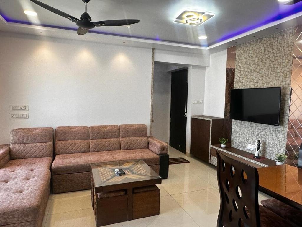 ein Wohnzimmer mit Sofa und Flachbildfernseher in der Unterkunft Skyline Oshiwara 2bhk-Andheri in Mumbai