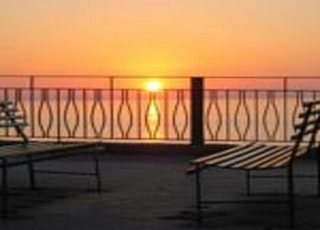 two benches sitting on a balcony watching the sunset at Terrazza Sul Mare in Gioiosa Marea