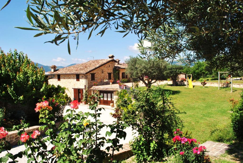 a house with a garden with flowers in the foreground at Agriturismo L'Antico Oliveto in San Severino Marche