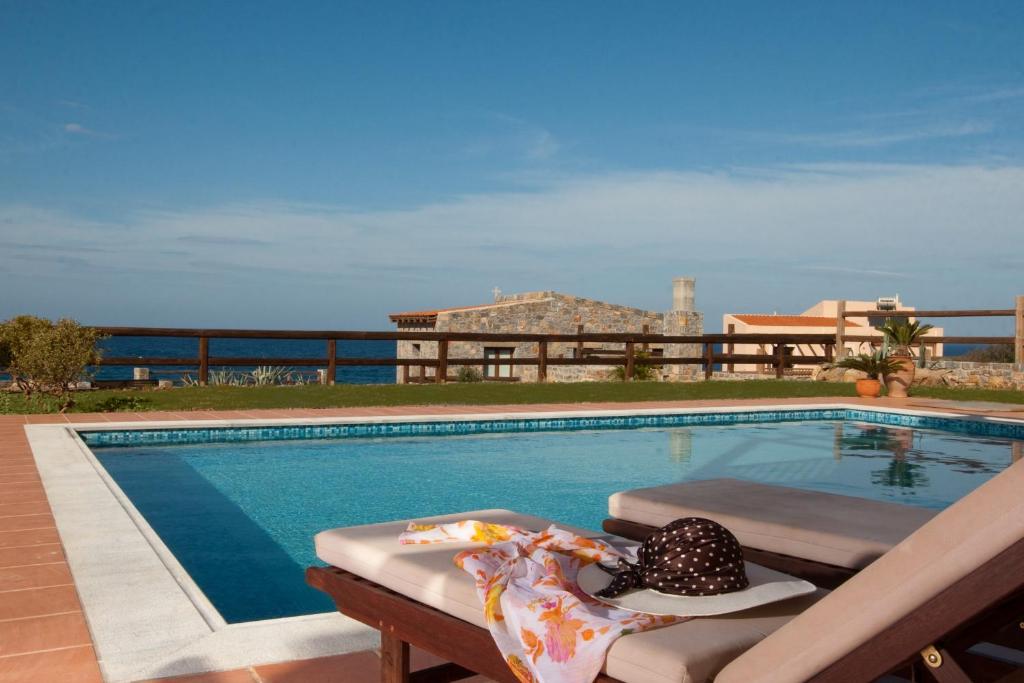 a swimming pool with a hat sitting on a bench next to it at Vasia Villas in Milatos