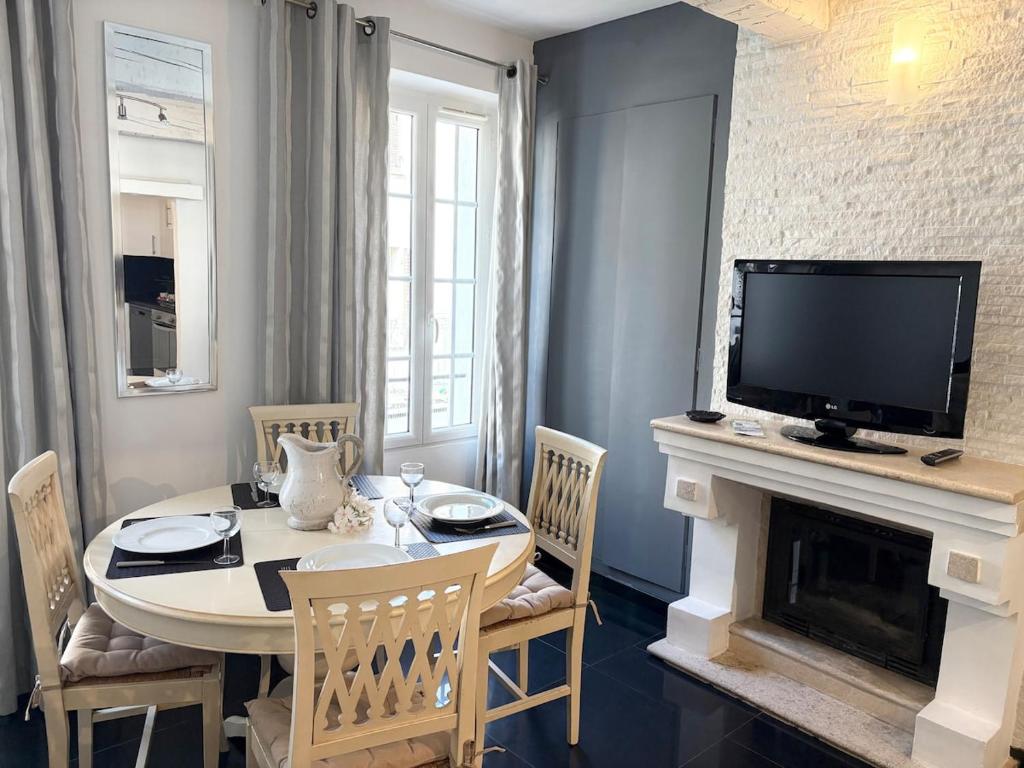 - un salon avec une table, une télévision et une cheminée dans l'établissement Véritable Cocon T3 centre historique Sainte-Maxime, à Sainte-Maxime