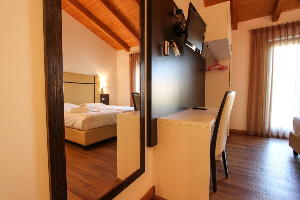 uma sala com um quarto com uma cama e um espelho em Thai Orchidee Restaurant&Rooms em Garda