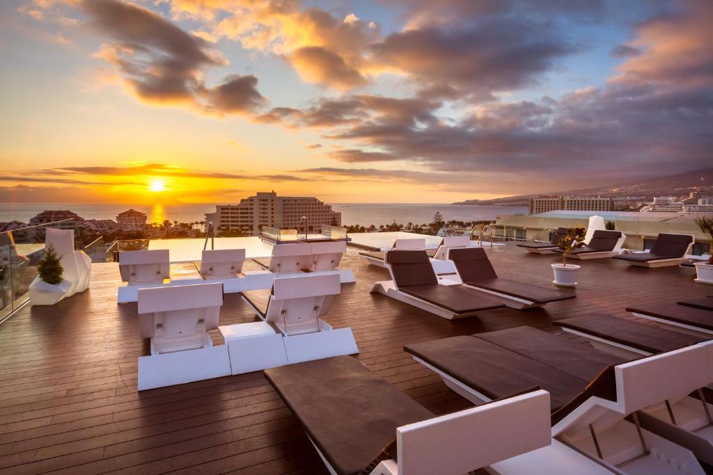 a rooftop patio with lounge chairs and a sunset at Tigotan Lovers & Friends Playa de las Americas - Adults Only (+18) in Playa de las Americas