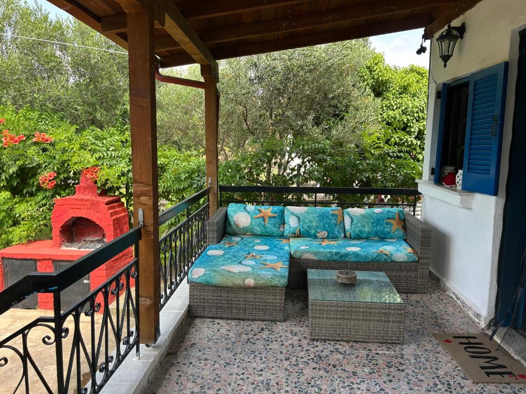 a patio with a couch and a fireplace on a balcony at 600 metres from the beach! in Nea Irakleia