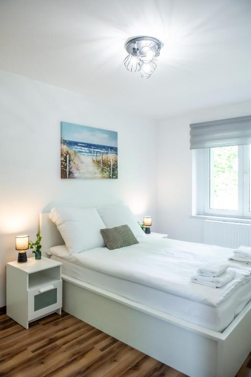 a white bedroom with a large bed and a window at Apartament Lipowa 26 in Gliwice