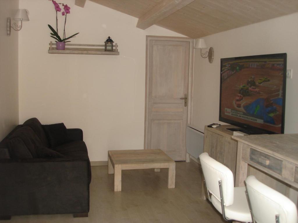 a living room with a couch and a tv and a table at Locations Ile de Ré in Sainte-Marie-de-Ré
