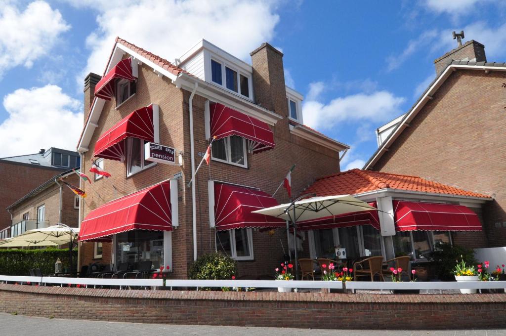 un edificio con toldos rojos y un restaurante en Pension Schier en Zandvoort