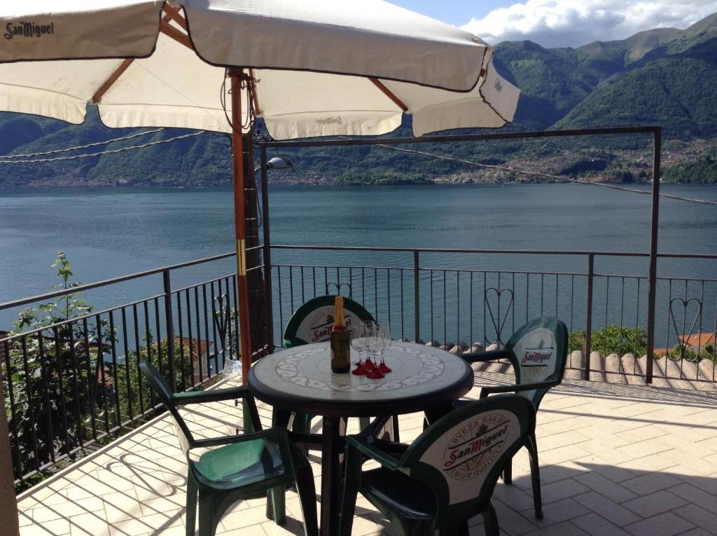 a table with chairs and an umbrella on a balcony at La sorgente in Lezzeno