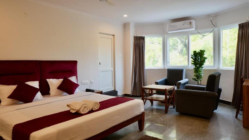 een hotelkamer met een bed, een bureau en stoelen bij Heritage Suites in Mysore