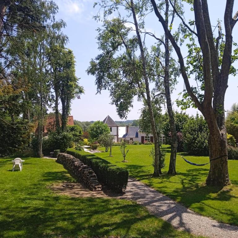 un jardin avec un mur en pierre et des arbres dans l'établissement le bien l'authie, à Colline-Beaumont