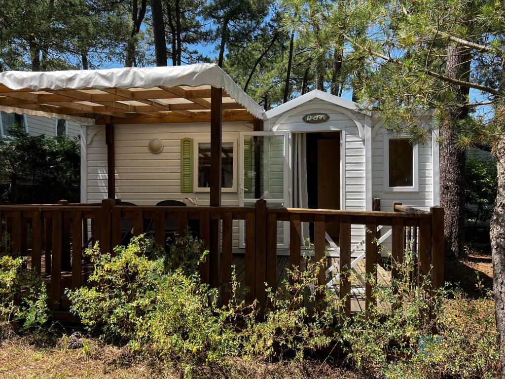 une petite maison blanche avec une clôture en bois dans l'établissement MOBIL HOME proche de la mer, à Grand-Village-Plage