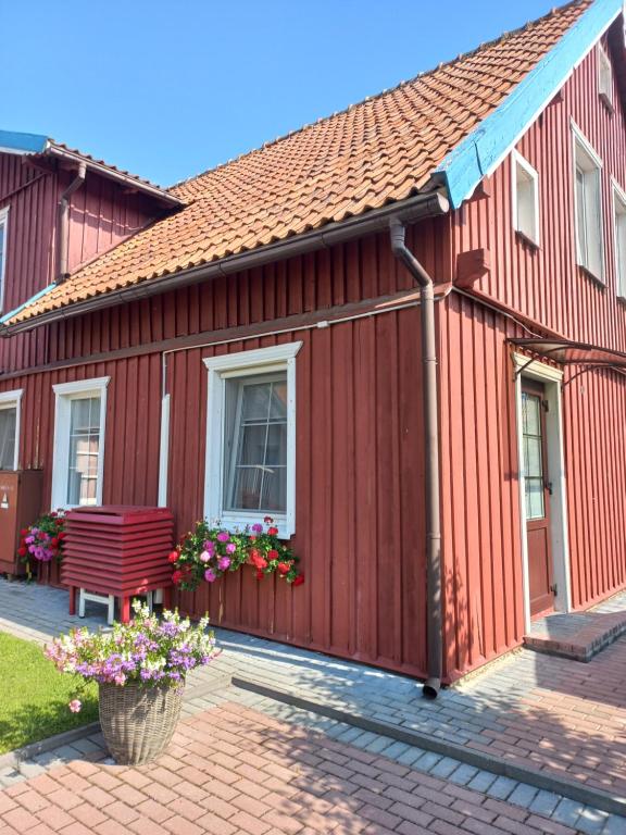 a red house with a bench in front of it at Ramus poilsis in Nida