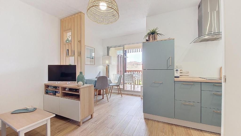 Il comprend une cuisine équipée d'un grand réfrigérateur et d'une table. dans l'établissement V-Landes 10-Joli petit appartement proche lac marin dans résidence avec piscine, à Vieux-Boucau-les-Bains