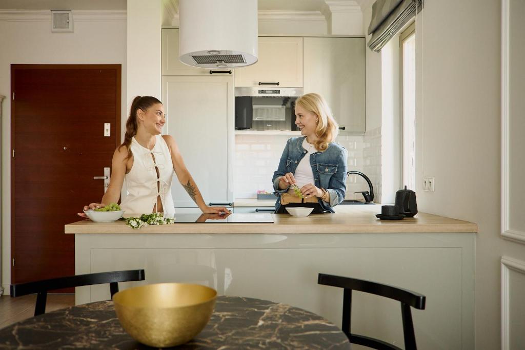 zwei Frauen stehen in einer Küche und reden in der Unterkunft Waterlane Riverside - SPA, Pool, Gym &amp; Parking by Downtown Apartments in Danzig