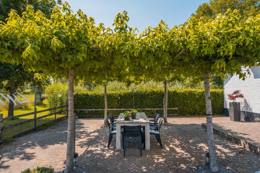 a table and chairs under two trees in a yard at Stijlvol & ruim relax vakantiehuis 'De Meierij' in Schijndel