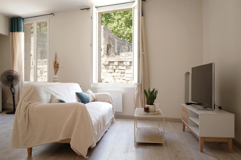 une chambre blanche avec un lit et une télévision dans l'établissement Studio lumineux intra-muros, à Avignon