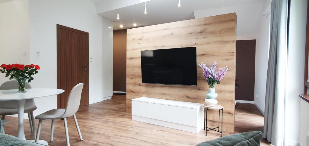 ein Wohnzimmer mit Fernseher und Tisch und Stühlen in der Unterkunft Willa Matejki - Apartament 8b in Przemyśl