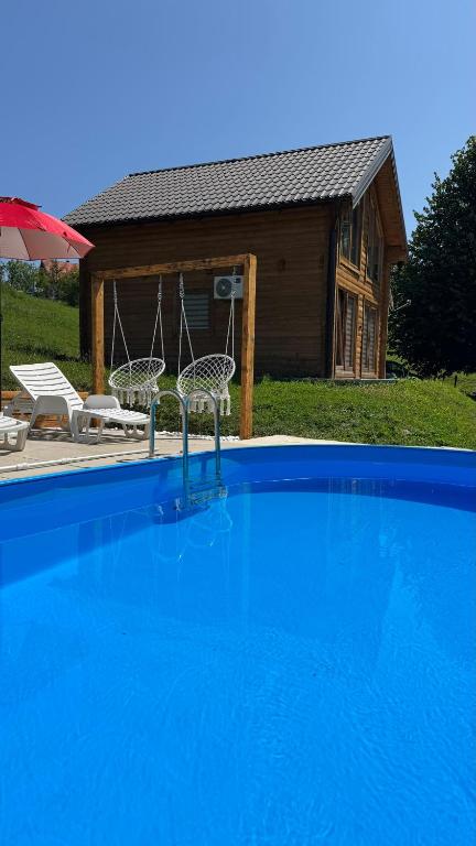 a swimming pool with two chairs and a house at Vikendica Brvnara Marčetić in Banja Luka