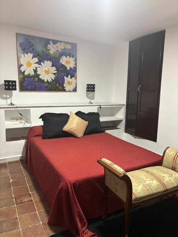 a bedroom with a red bed with a painting on the wall at Casa cubo in Alhama de Granada
