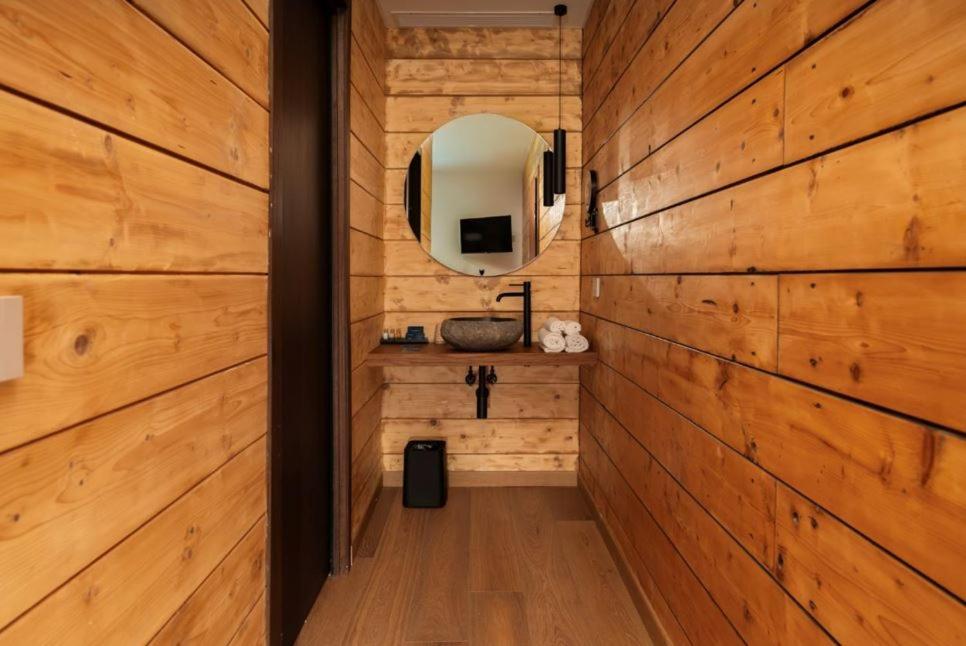 a bathroom with wooden walls and a mirror and a sink at Nabi Resort Glamping & SPA in Castel Volturno