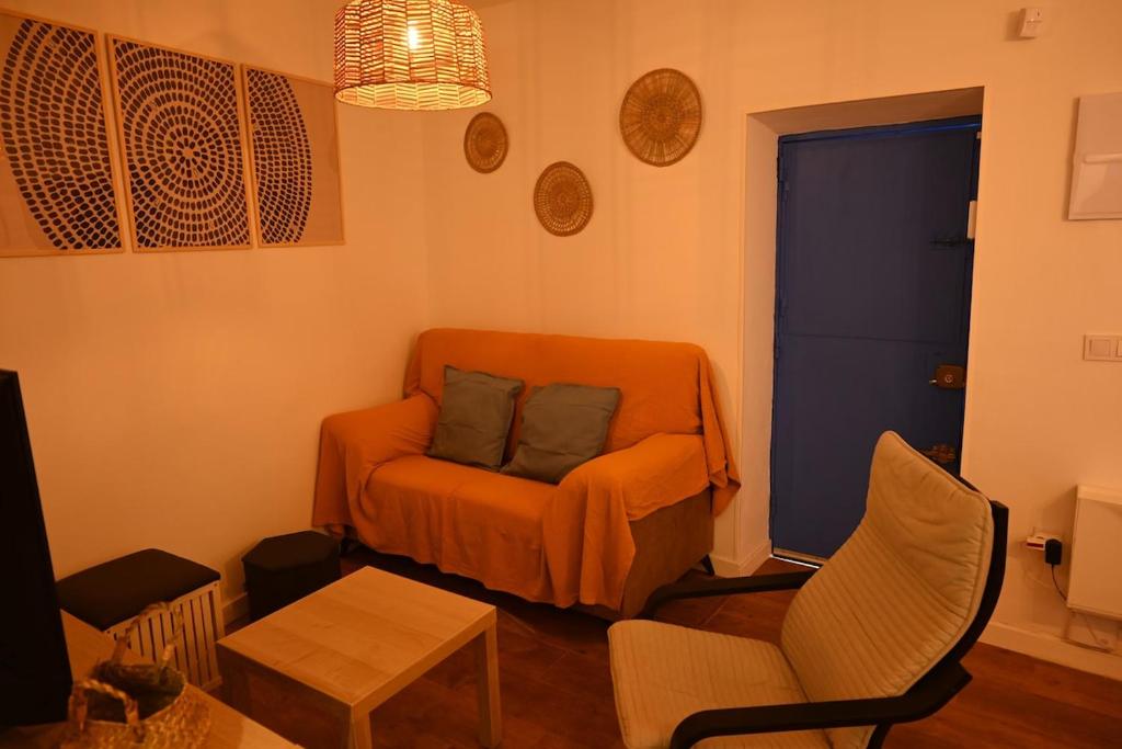 a living room with an orange couch and chairs at Casa en casco antiguo de Barbate in Barbate