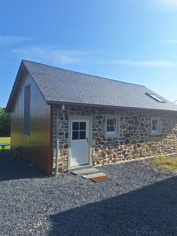 a small stone building with a white door and a stone wall at Chez Théo in Trois-Ponts