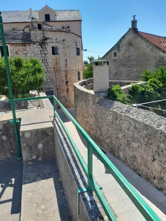 a green railing in front of some buildings at Studio apartman Marija in Bol