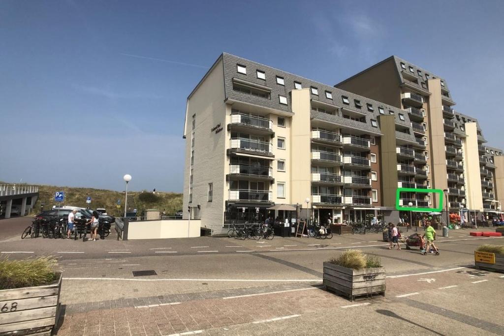 Un gran edificio con un estacionamiento enfrente. en Duinroosje, en Cadzand