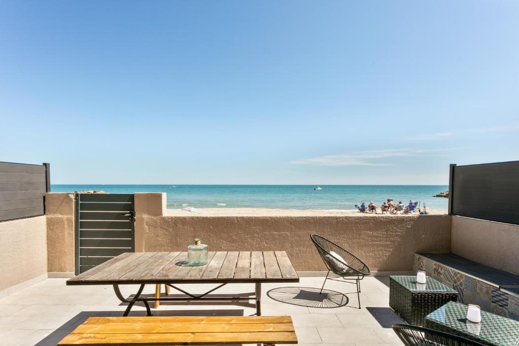une terrasse avec une table et des chaises et la plage dans l'établissement appartement 1ère ligne face à la mer, à Palavas-les-Flots