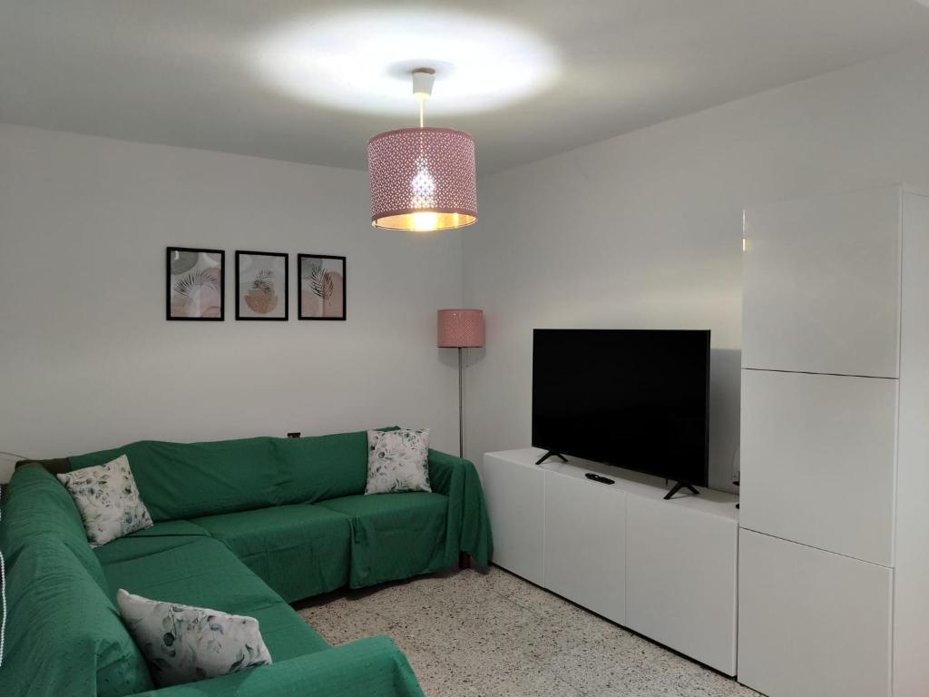 a living room with a green couch and a flat screen tv at Guesthouse Los Geranios in Mocanal