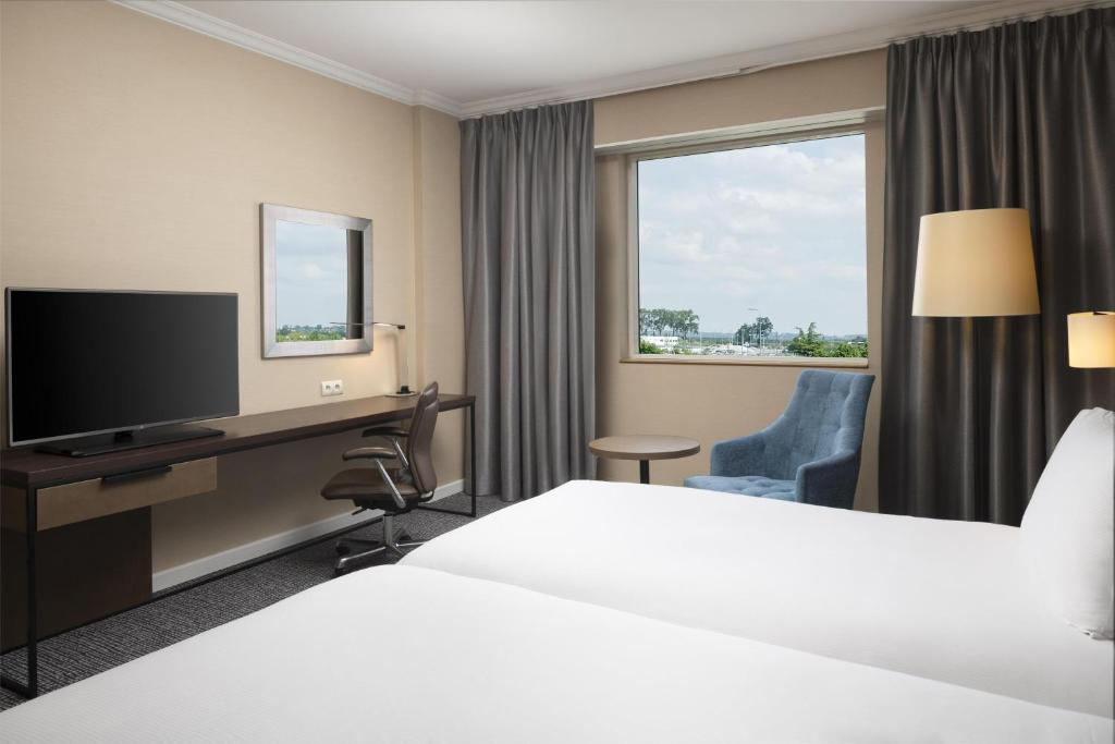 a hotel room with a bed and a desk and a television at Hilton Paris Charles De Gaulle Airport in Roissy-en-France