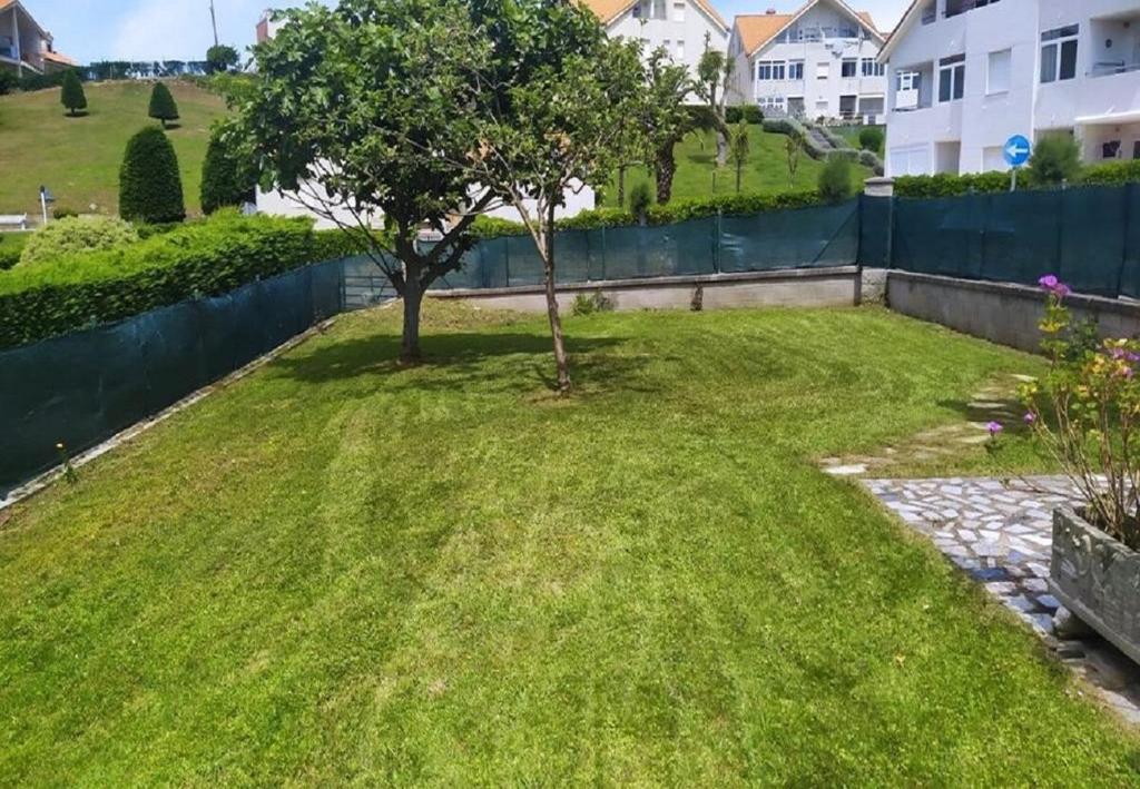 a yard with a tree in the middle of it at Mogro Las Dunas - Relax Total en Apartamento con Jardín in Miengo