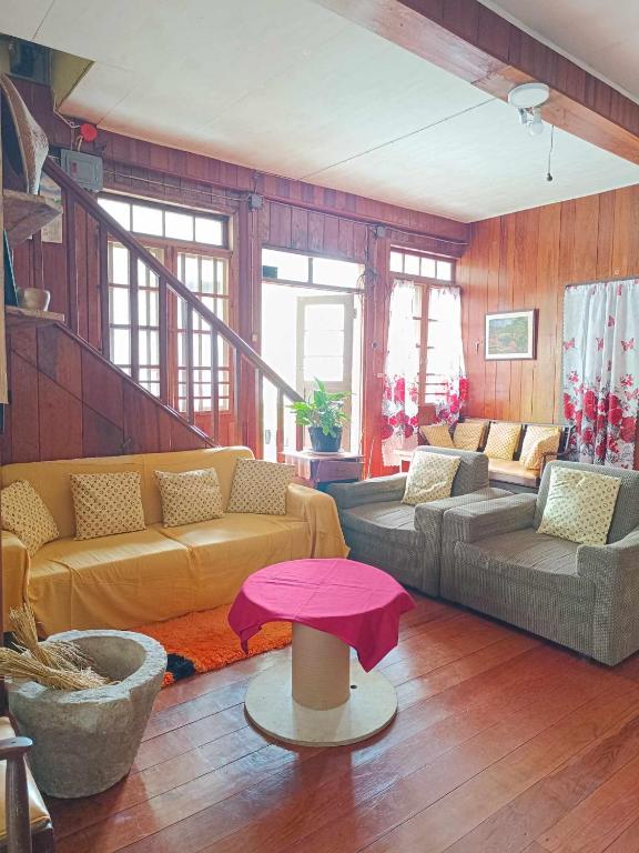 a living room with yellow couches and a pink table at A-Seven House Sagada in Sagada