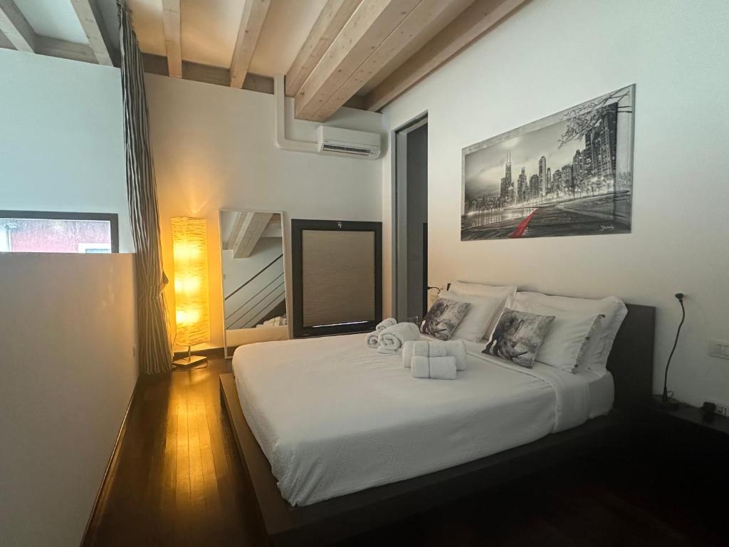 una camera da letto con un letto bianco con un quadro sul muro di RED LOFTY Milano- Loft moderno comodo per Ippodromo, San Siro, Rho Fiera-MiCo e Politecnico, parking a Milano