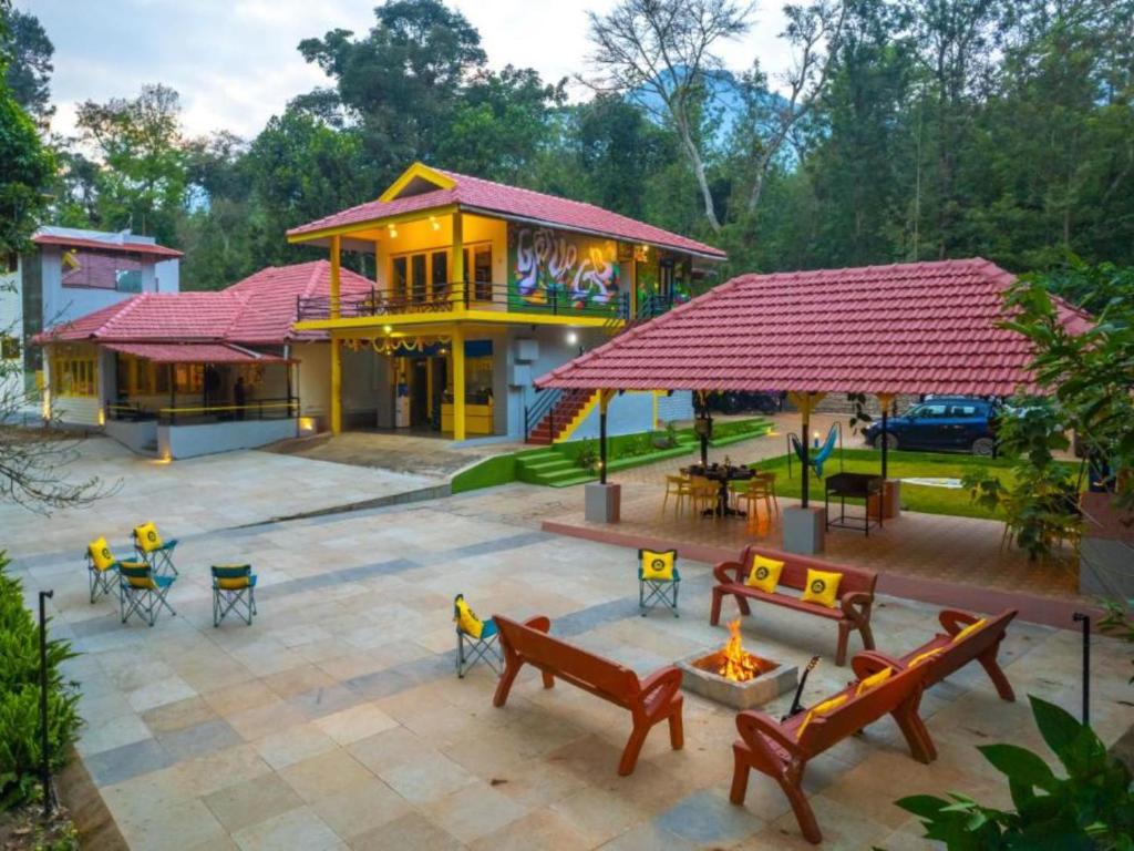 a building with benches and tables in front of it at The Hosteller Chikmagalur in Chikmagalūr