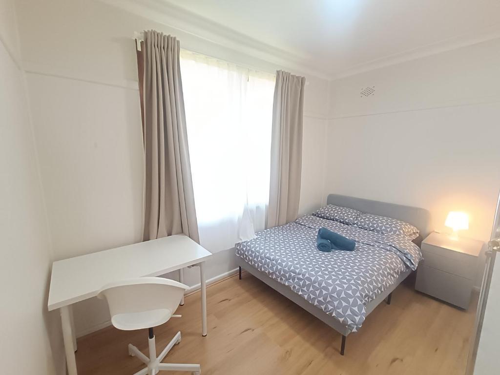 a bedroom with a bed and a desk and a window at Queen Room in West Ryde Home - E1 in Sydney