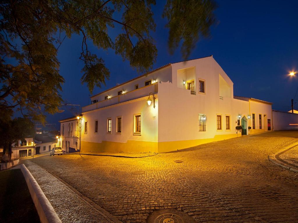 a white building on a cobblestone street at night at Betica Hotel Rural in Pias