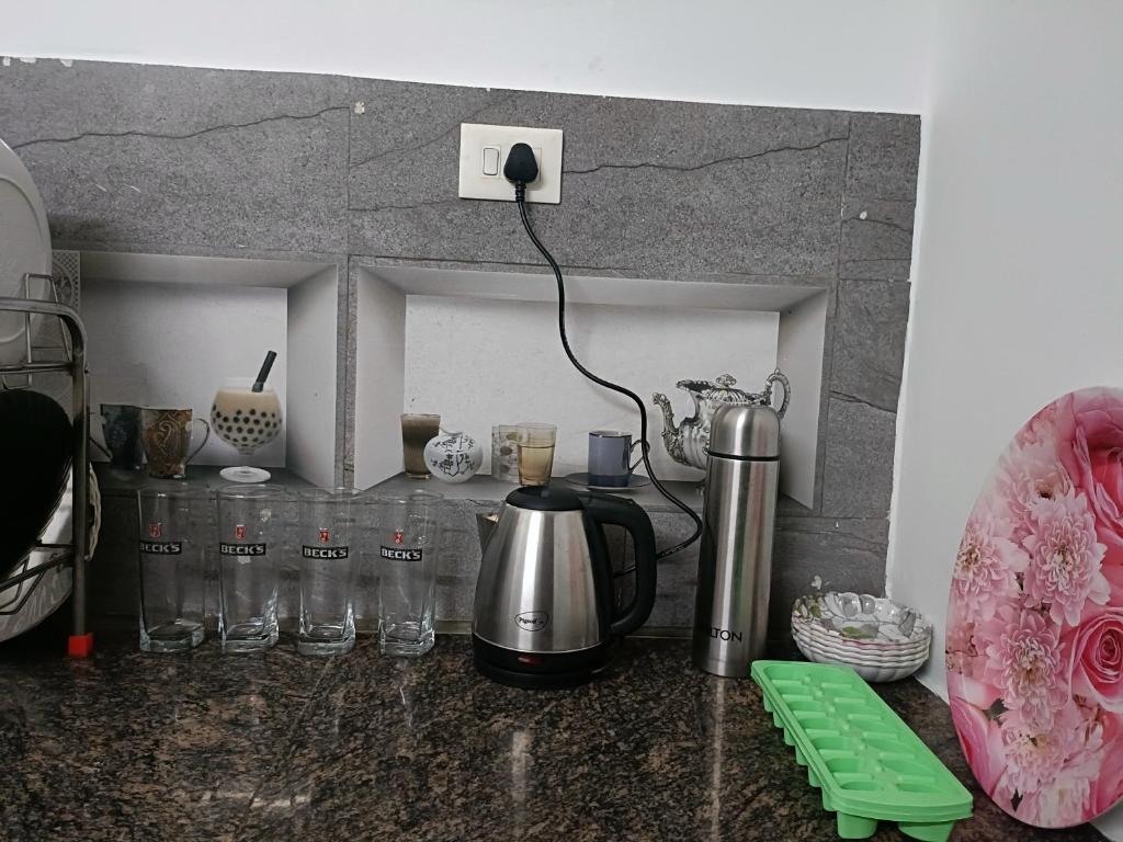 a kitchen counter with a coffee pot and glasses on it at Le Escape Homey in Puducherry