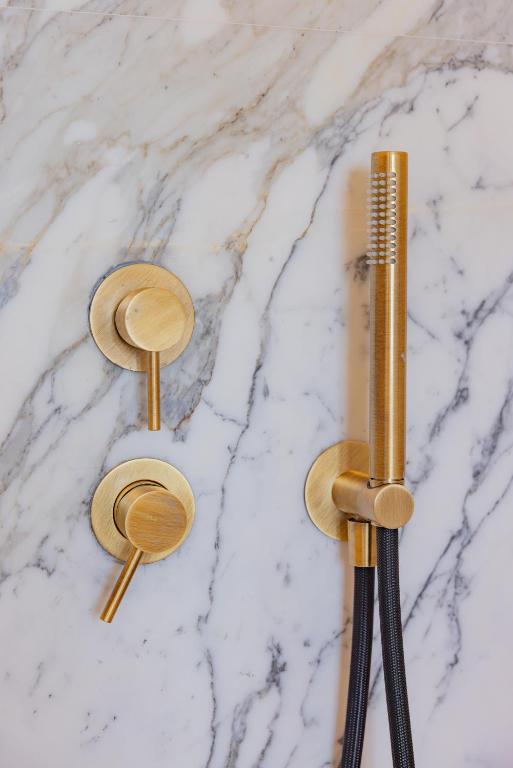 two gold showerheads and a comb on a marble counter at Hotel Belvedere in Forte dei Marmi