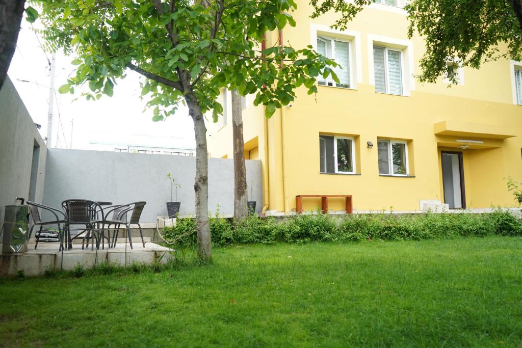a table and chairs under a tree in a yard at Hotel AKSU in Bucharest