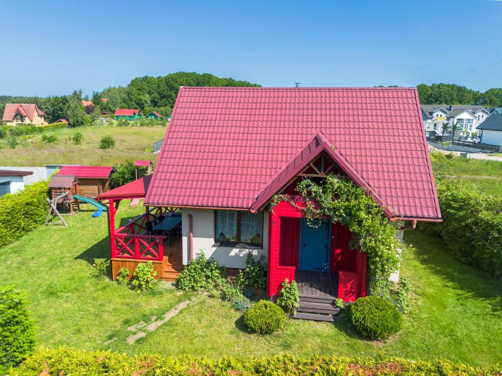 a small house with a red roof on a green field at Korsarz in Rusinowo