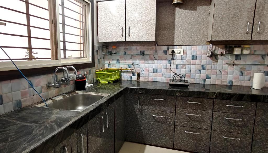a kitchen with a sink and a counter top at Kanakdhara Homestay in Ujjain