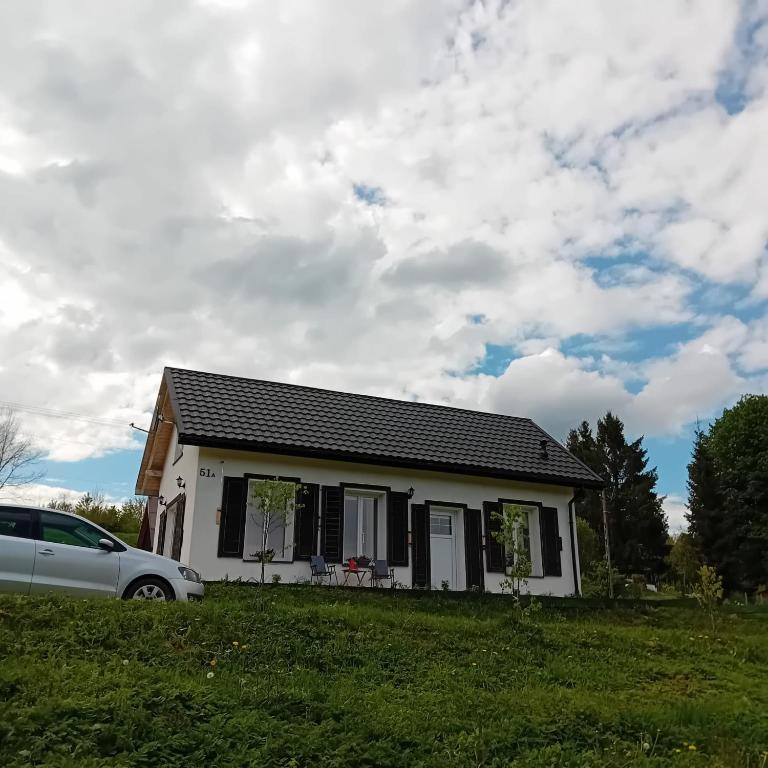 a white house with a car parked in front of it at Domek Kaprys Piatkowa 