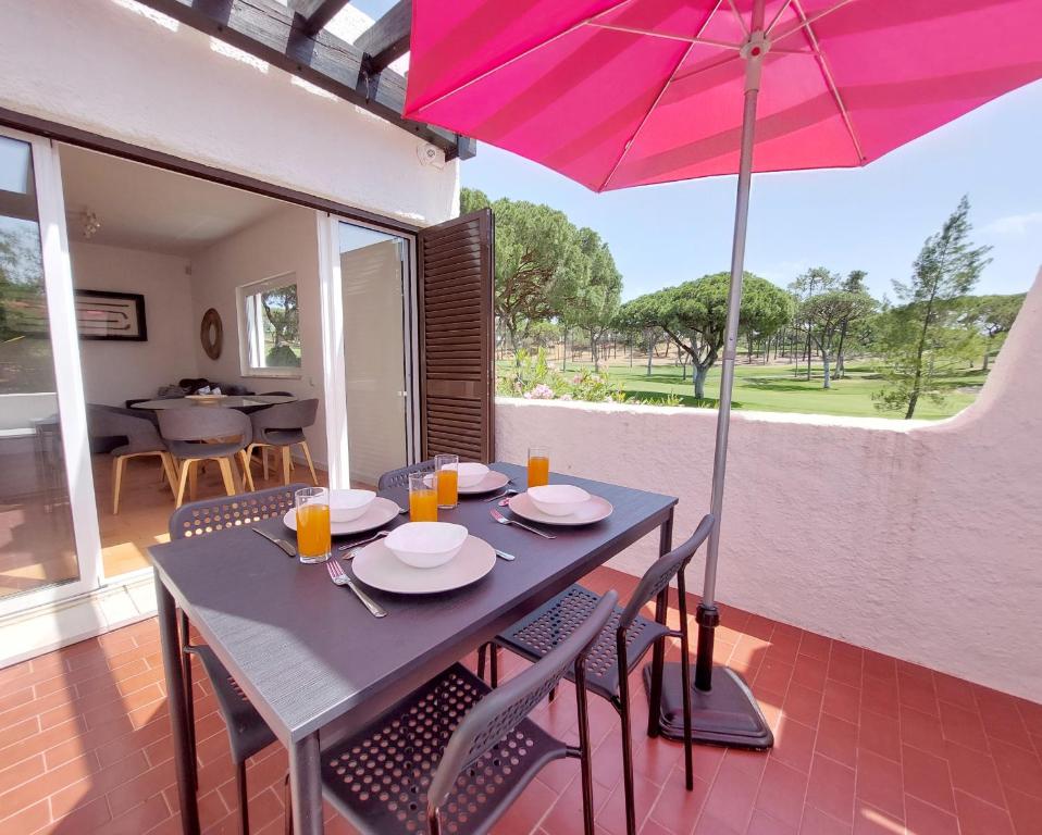 Una mesa y sillas con una sombrilla en un patio. en V2 - Bungalow 12, en Quarteira