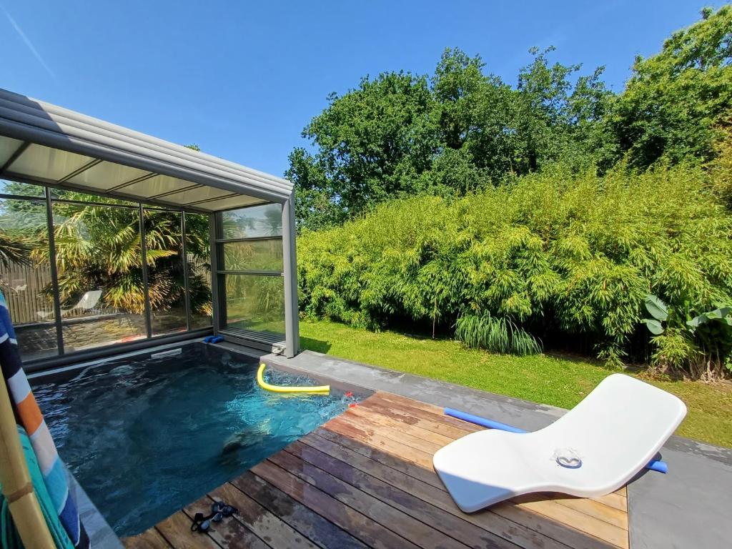 une piscine avec une terrasse et une chaise blanche dans l'établissement Magnifique maison contemporaine piscine chauffée, à Crozon