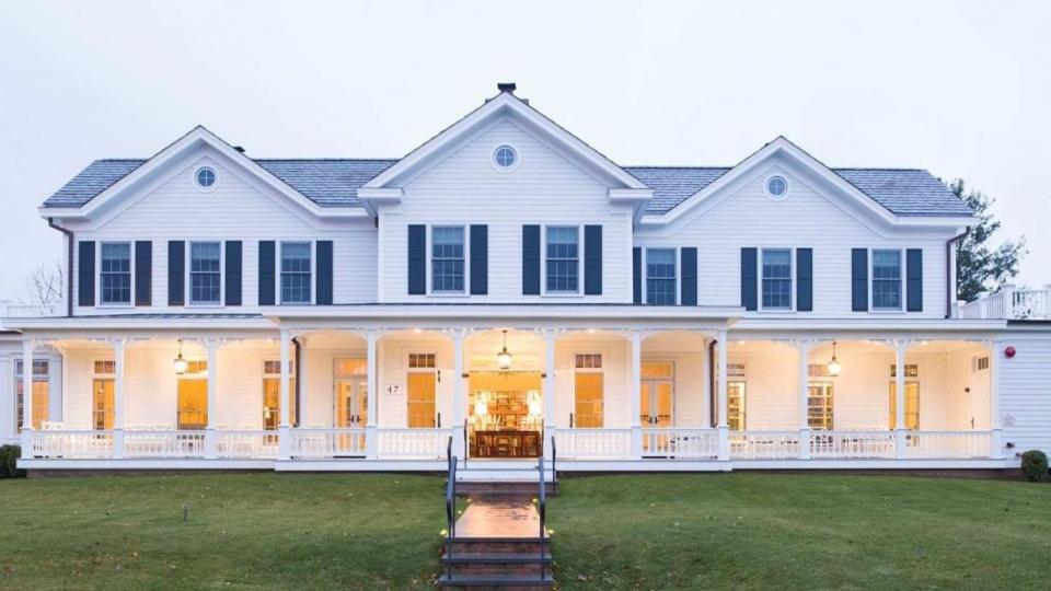 una grande casa bianca con un cortile anteriore di The Quogue Club a Quogue