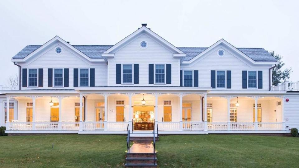 a large white house with a front yard at The Quogue Club in Quogue