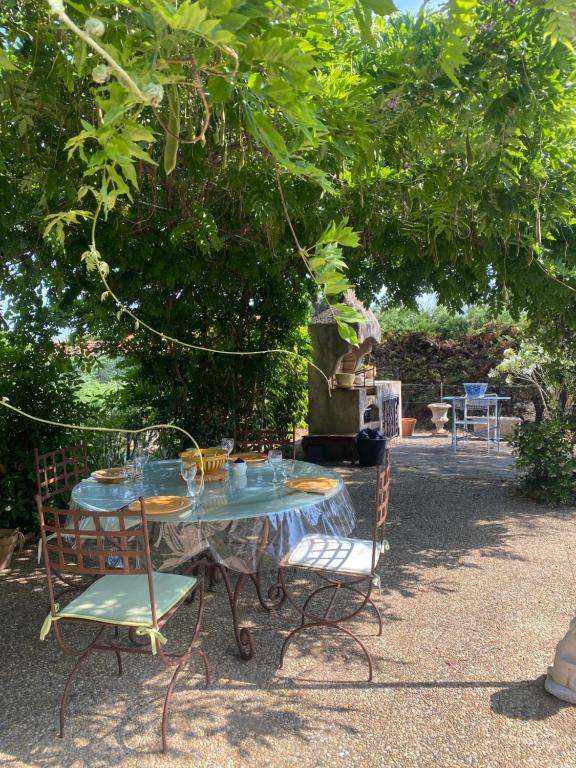 une table avec des chaises assises sous un arbre dans l'établissement Maison Juliana centre village et navette plage, à La Croix-Valmer