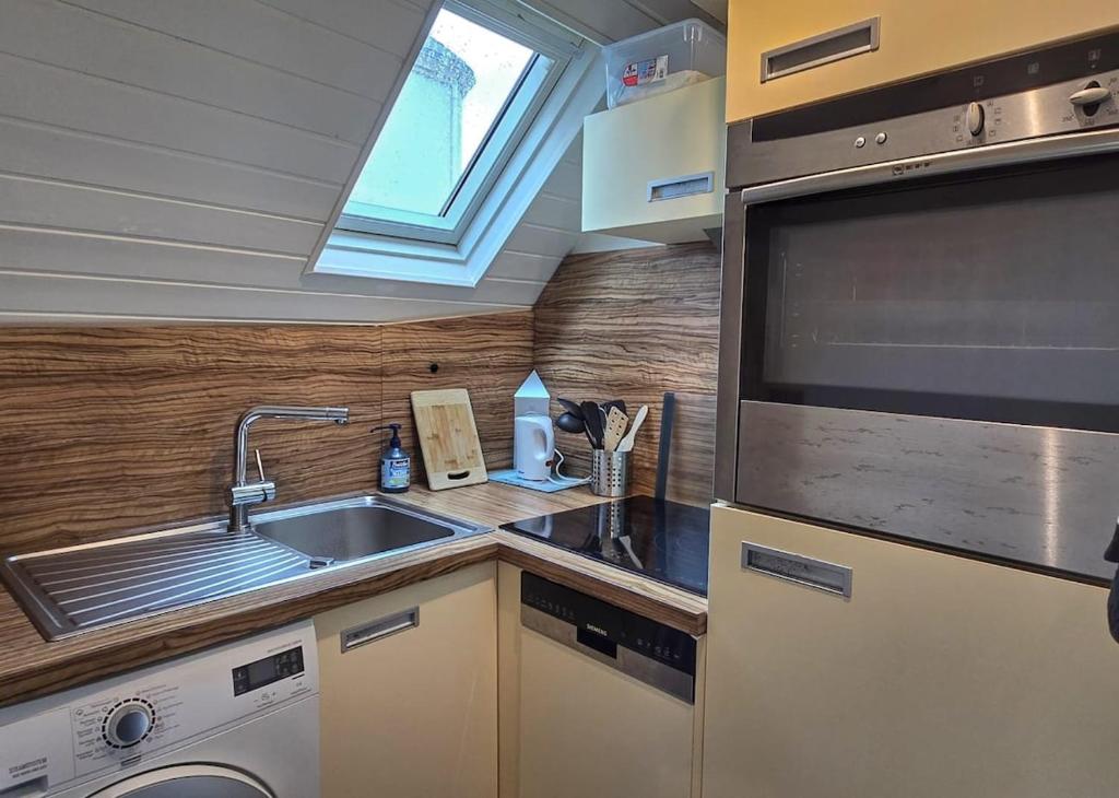 une cuisine avec un évier et une machine à laver dans l'établissement Appartement vue mer, Centre-ville & plage, à Quiberon