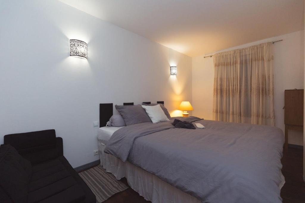 a bedroom with a large bed and a chair at Appartements des Compagnons in Val de Reuil